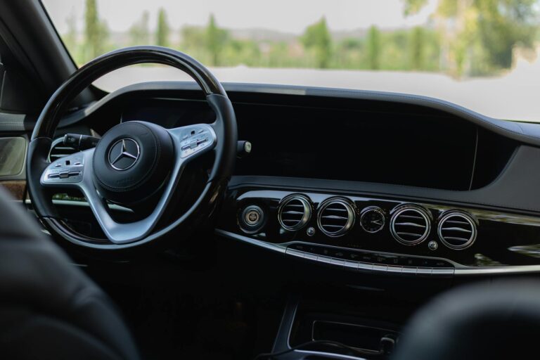Detail view of a luxury car's steering wheel and dashboard showcasing elegance.