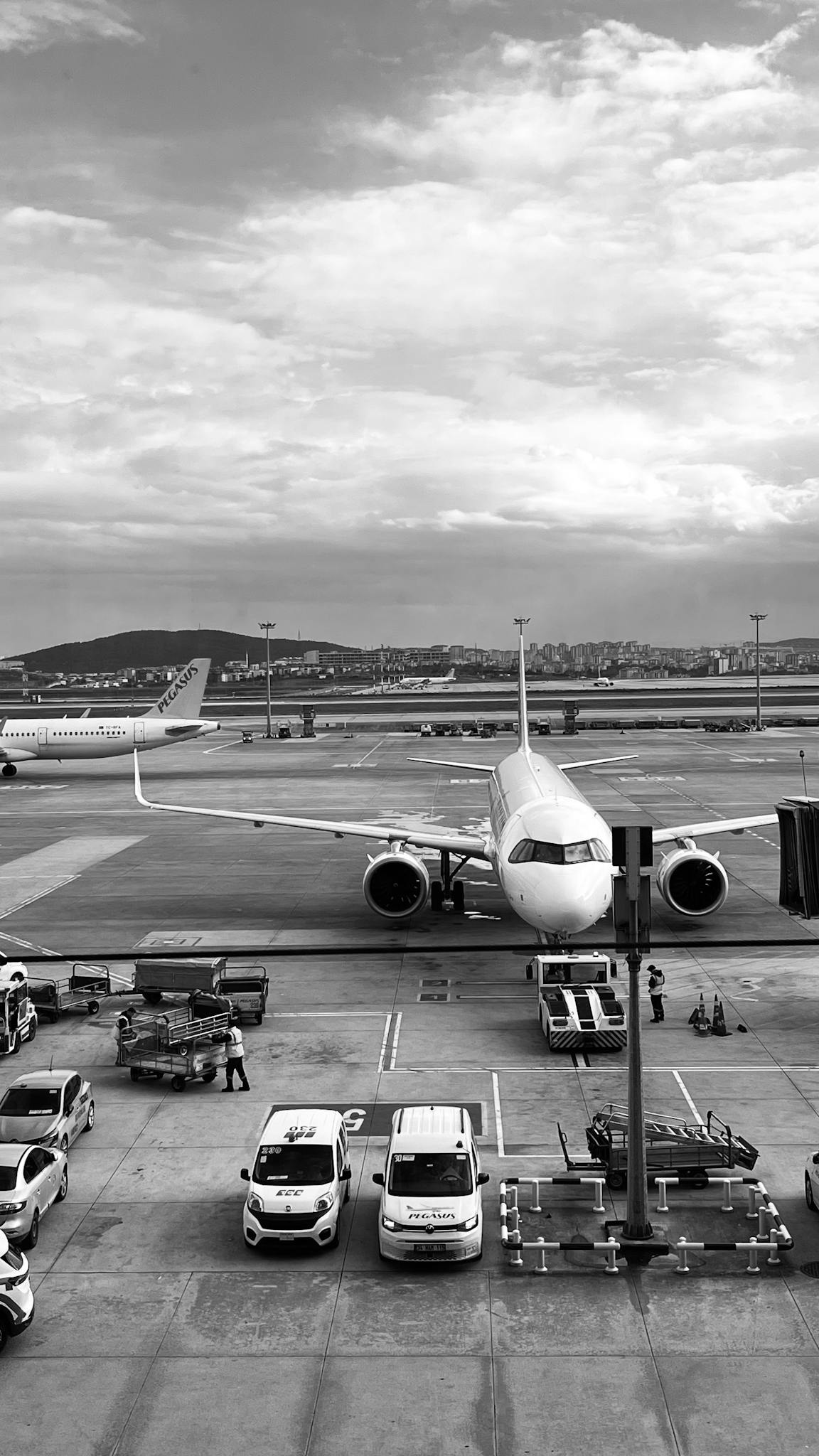 Monochrome image of an airplane parked at the airport runway ready to board passengers.