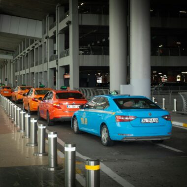 Vibrant taxis lined up at Istanbul Airport arrival terminal with passengers and drivers interacting.